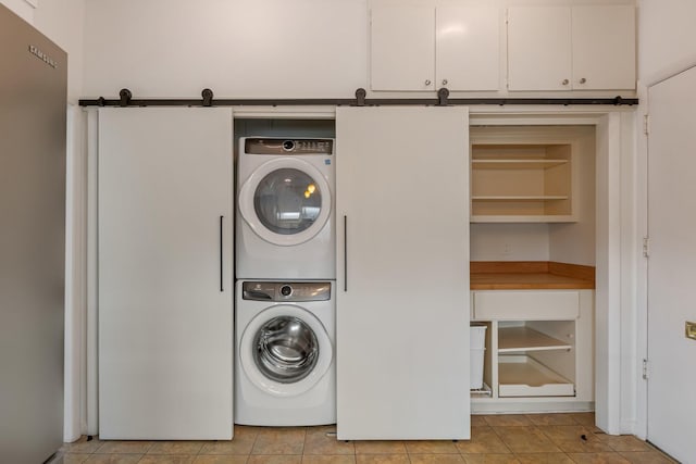 laundry room featuring laundry area, light tile patterned floors, and stacked washer / drying machine