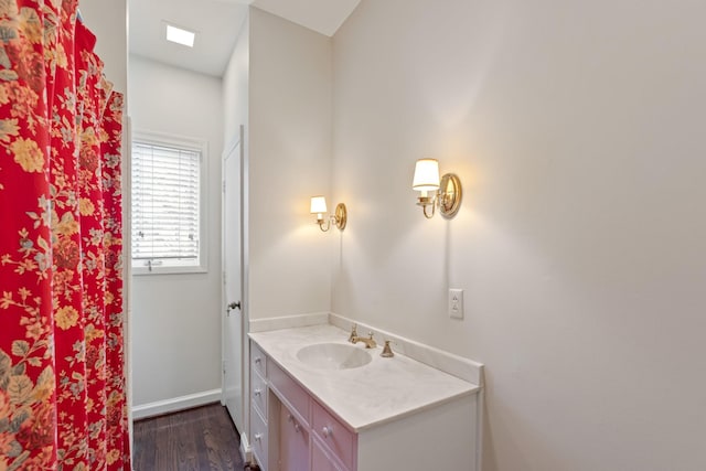bathroom with baseboards, wood finished floors, and vanity