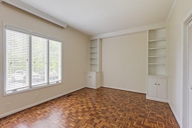 spare room featuring crown molding, built in features, and baseboards