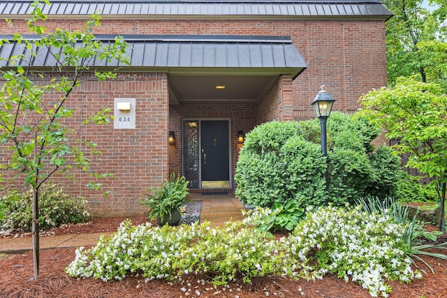 entrance to property with brick siding, metal roof, and a standing seam roof