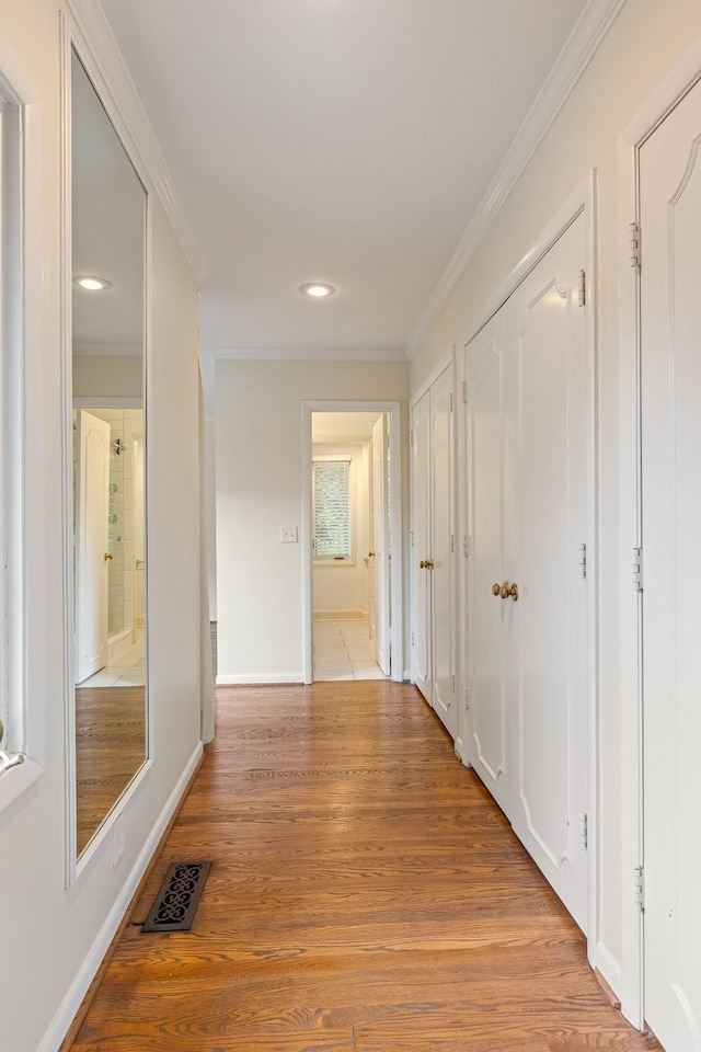 hallway with visible vents, recessed lighting, crown molding, and light wood-type flooring