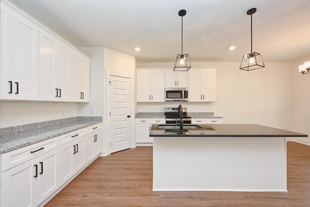 kitchen featuring an island with sink, recessed lighting, a sink, light wood finished floors, and appliances with stainless steel finishes