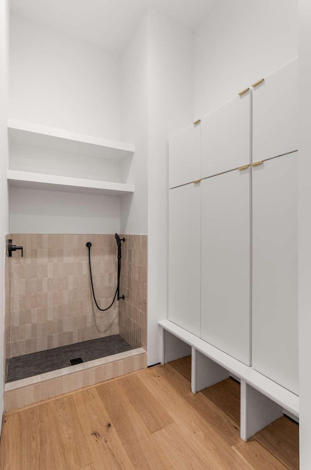 full bathroom featuring wood finished floors and tiled shower