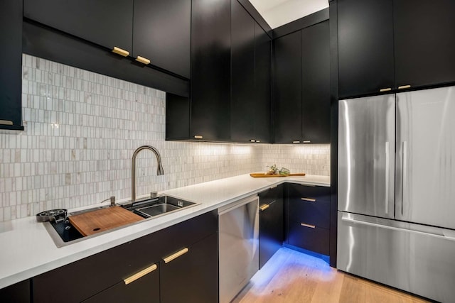 kitchen featuring dark cabinets, light countertops, tasteful backsplash, and stainless steel appliances