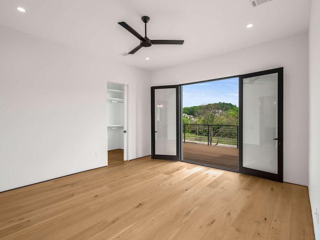 unfurnished bedroom with a spacious closet, recessed lighting, light wood-style flooring, and access to exterior