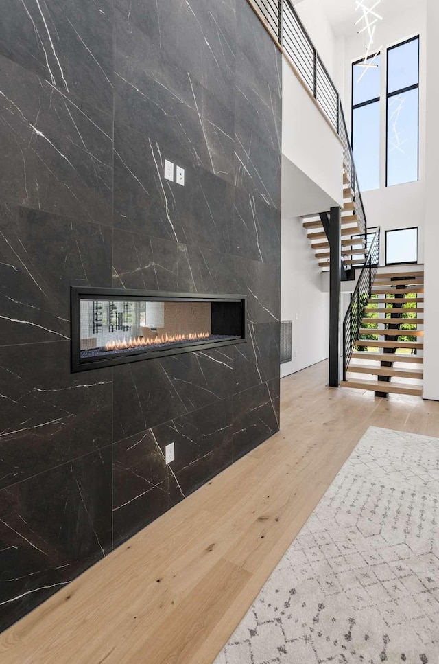 foyer entrance featuring a multi sided fireplace, a high ceiling, stairs, and wood finished floors