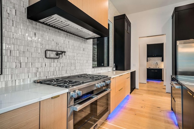 kitchen with modern cabinets, range with two ovens, custom range hood, a sink, and backsplash