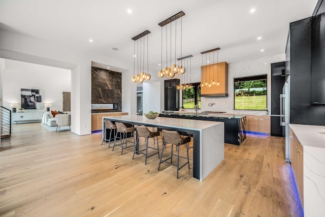 kitchen featuring a breakfast bar, light wood-style floors, a large island, modern cabinets, and light countertops