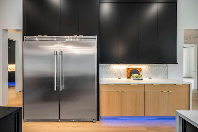 kitchen with dark cabinets, light countertops, tasteful backsplash, and stainless steel built in refrigerator