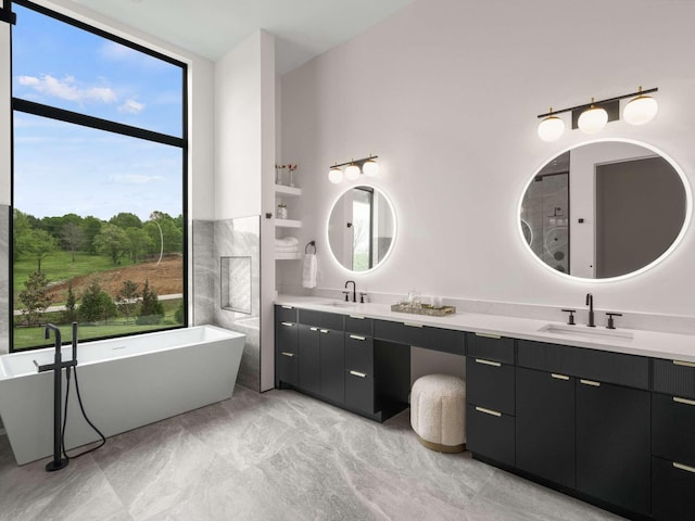 bathroom with double vanity, a sink, marble finish floor, and a soaking tub