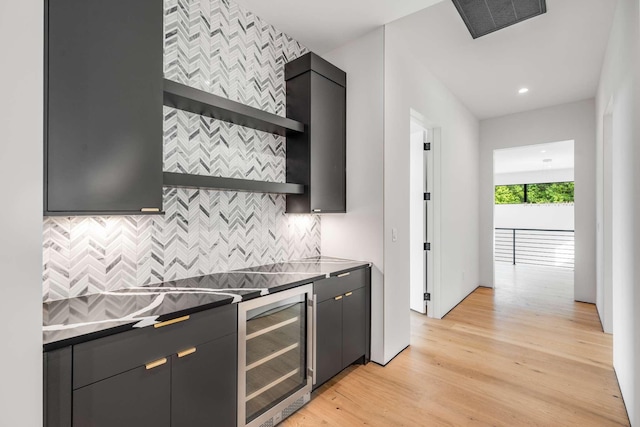 kitchen featuring tasteful backsplash, open shelves, beverage cooler, dark cabinetry, and light wood-style flooring