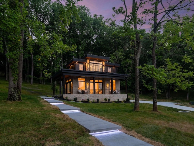 view of front of property with covered porch, a front yard, and stone siding