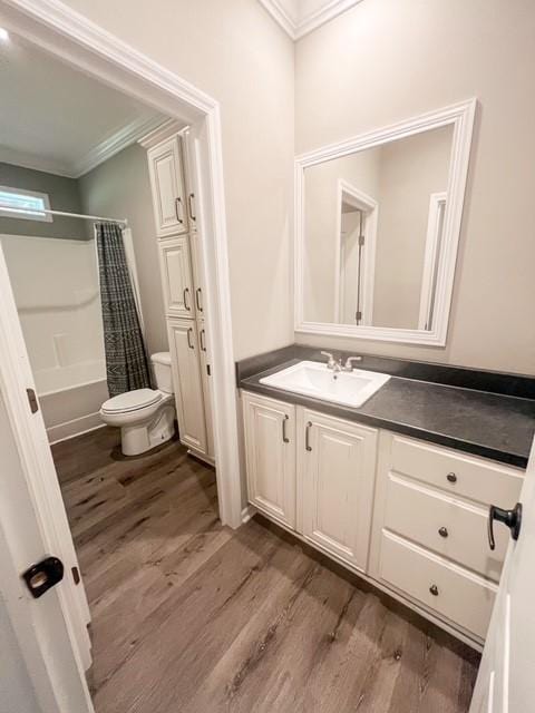 bathroom with toilet, ornamental molding, wood finished floors, and vanity