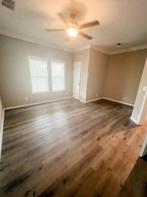 unfurnished bedroom with visible vents, ornamental molding, baseboards, and wood finished floors