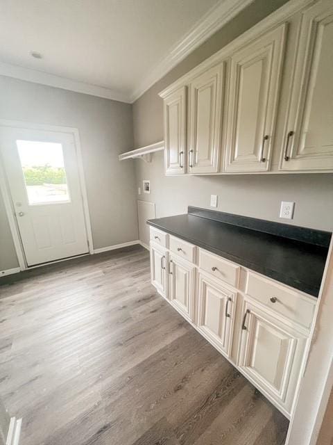 washroom with crown molding, light wood-style floors, cabinet space, and hookup for a washing machine