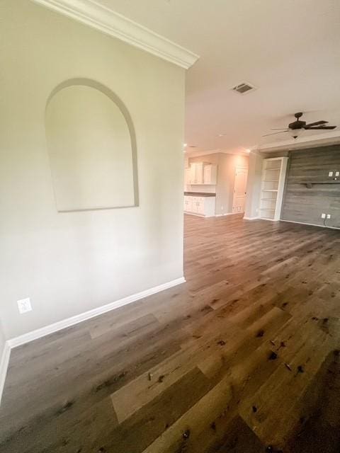 interior space with crown molding, baseboards, wood finished floors, and visible vents