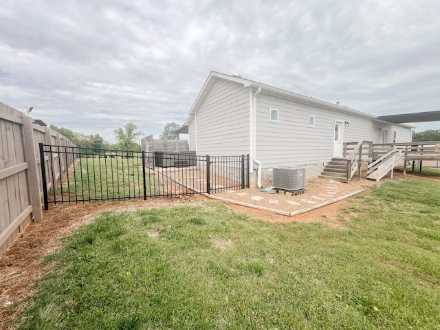 rear view of house featuring a lawn, cooling unit, and a fenced backyard