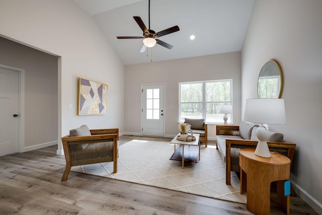 living room featuring baseboards, a ceiling fan, high vaulted ceiling, and wood finished floors