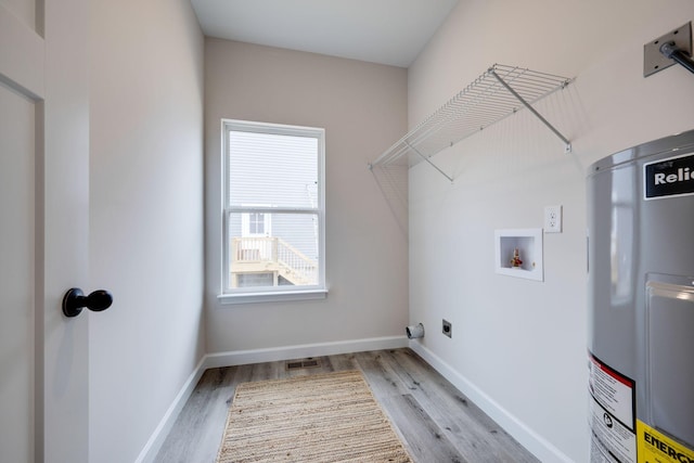 clothes washing area featuring laundry area, water heater, wood finished floors, and electric dryer hookup