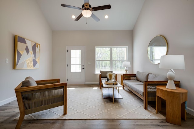 interior space with ceiling fan, baseboards, lofted ceiling, and wood finished floors