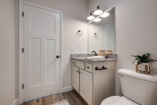 bathroom with toilet, baseboards, wood finished floors, and vanity
