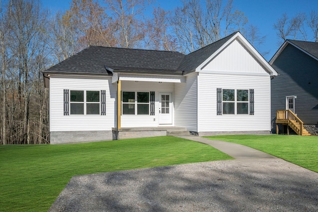 view of front of home with roof with shingles and a front yard