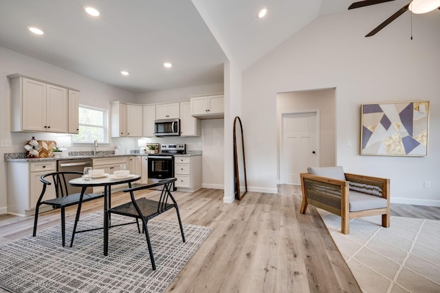 kitchen featuring light wood-type flooring, a ceiling fan, baseboards, and appliances with stainless steel finishes