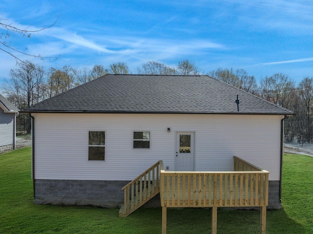 back of property with a wooden deck, a shingled roof, and a yard