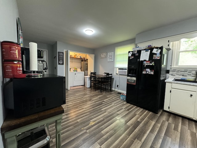 kitchen with black fridge with ice dispenser, white cabinetry, separate washer and dryer, a sink, and dark wood finished floors