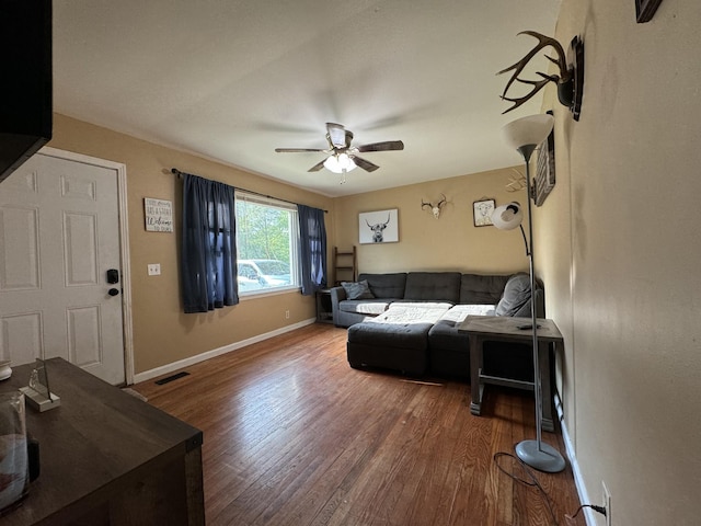 living room featuring baseboards, a ceiling fan, wood finished floors, and visible vents