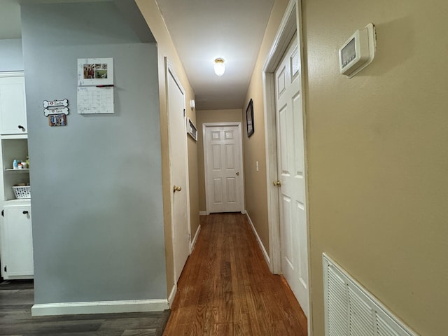 hallway with baseboards, dark wood-style floors, and visible vents
