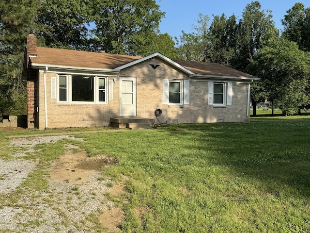 view of front of house featuring a chimney, a front yard, brick siding, and crawl space
