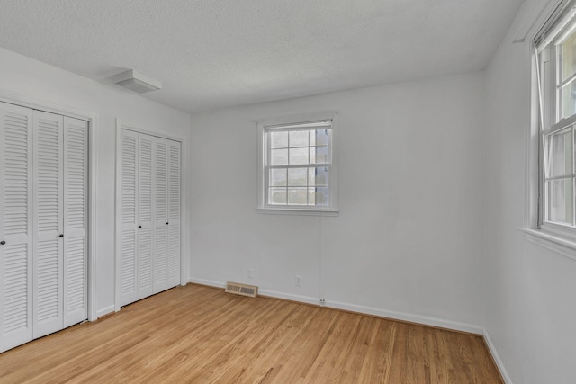 4043 Marydale Dr, Nashville, TN 37207 - unfurnished bedroom featuring a textured ceiling, multiple closets, light wood-style flooring, baseboards, and visible vents