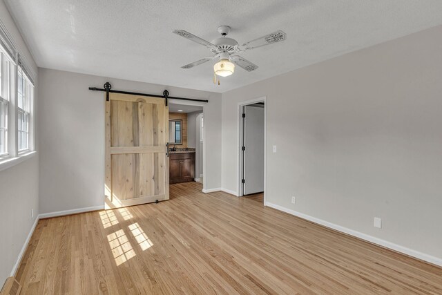 4043 Marydale Dr, Nashville, TN 37207 - unfurnished bedroom featuring light wood-style floors, baseboards, a textured ceiling, and a barn door