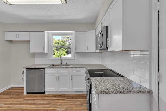 4043 Marydale Dr, Nashville, TN 37207 - kitchen with decorative backsplash, white cabinets, a sink, light wood-style flooring, and appliances with stainless steel finishes