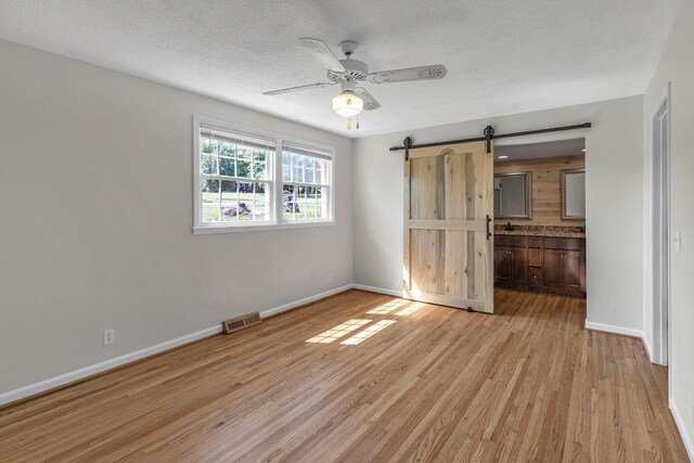 4043 Marydale Dr, Nashville, TN 37207 - unfurnished bedroom featuring visible vents, baseboards, a barn door, a textured ceiling, and light wood finished floors