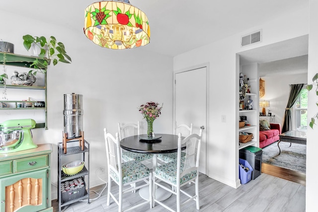 dining area with visible vents, baseboards, and light wood finished floors