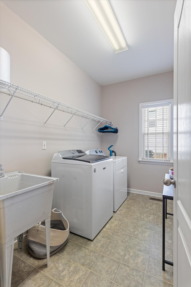 clothes washing area with washing machine and clothes dryer, laundry area, visible vents, and baseboards