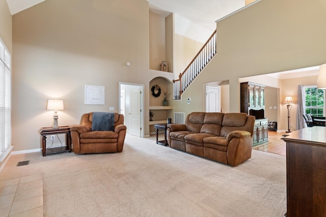 living area featuring high vaulted ceiling, baseboards, light colored carpet, and visible vents
