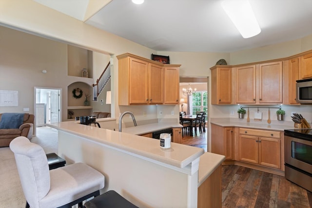 kitchen with open floor plan, a kitchen breakfast bar, light countertops, a chandelier, and appliances with stainless steel finishes
