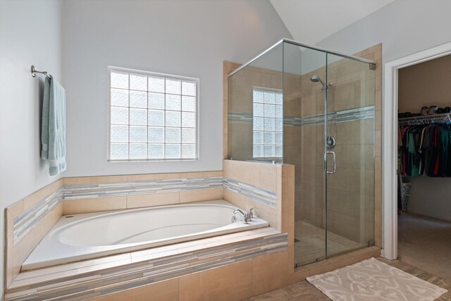 bathroom featuring lofted ceiling, a shower stall, a walk in closet, and a bath