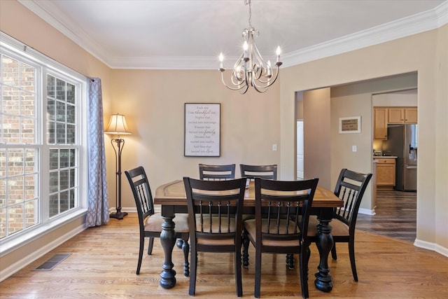 dining area with light wood-style floors, visible vents, ornamental molding, and a notable chandelier