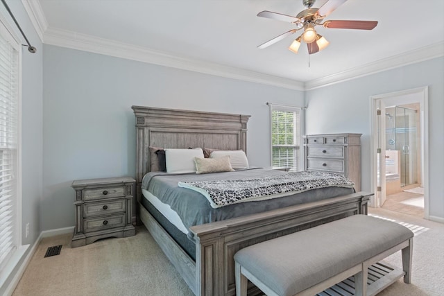 carpeted bedroom featuring visible vents, crown molding, baseboards, a ceiling fan, and ensuite bath