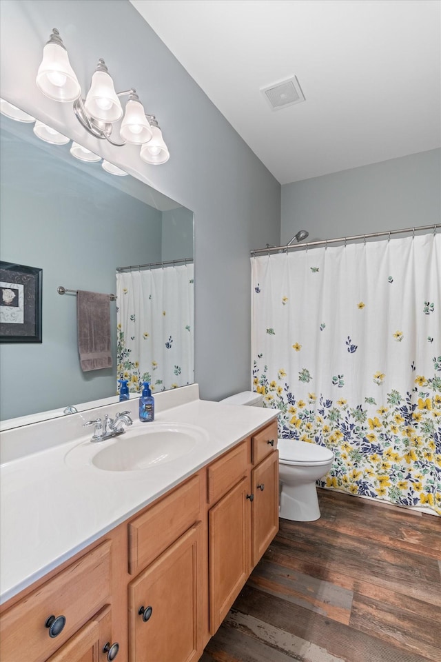 bathroom featuring vanity, toilet, curtained shower, wood finished floors, and visible vents