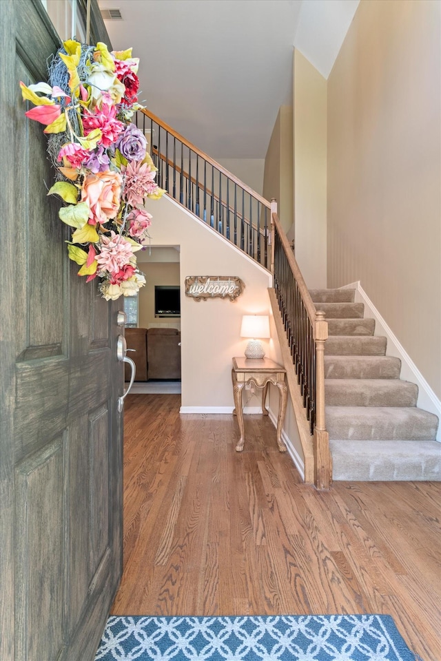 entrance foyer with stairway, baseboards, vaulted ceiling, and wood finished floors