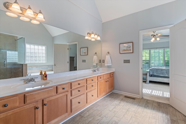 ensuite bathroom with wood finished floors, a sink, lofted ceiling, and a healthy amount of sunlight
