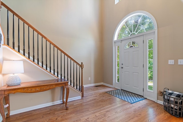 foyer entrance featuring baseboards, stairs, wood finished floors, and a towering ceiling