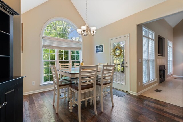 dining area with an inviting chandelier, high vaulted ceiling, a tile fireplace, visible vents, and dark wood-style floors