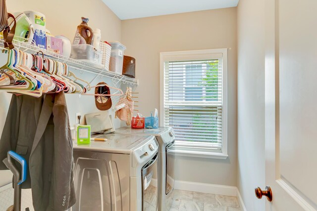 clothes washing area featuring separate washer and dryer, laundry area, and baseboards