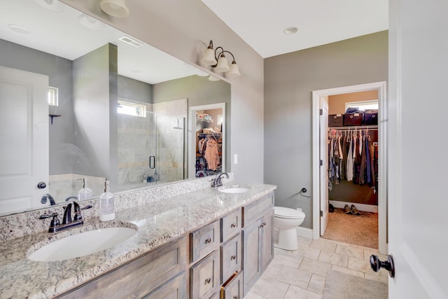 bathroom featuring double vanity, a spacious closet, a sink, and a stall shower